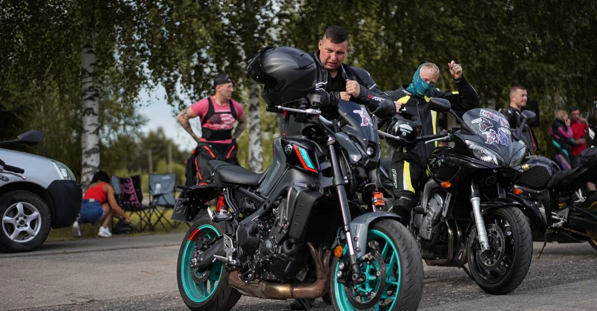 Groupe de motocyclistes ajustant leur équipement à côté des motos lors d'un rassemblement par un jour ensoleillé.